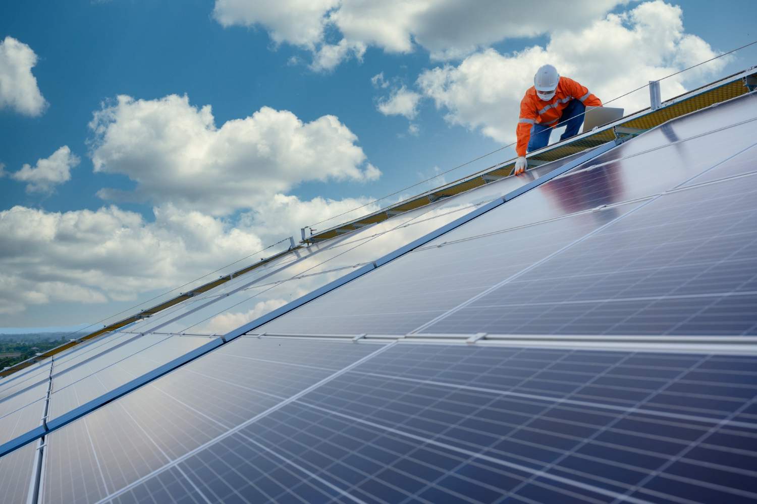 Homem instalando painel solar no topo de uma casa.